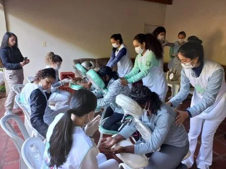 A imagem destacada é uma foto de uma ação de extensão universitária relacionada à área de saúde, onde estudantes de massoterapia, com a orientação de professores, vão até uma determinada localidade para oferecerem seus serviços