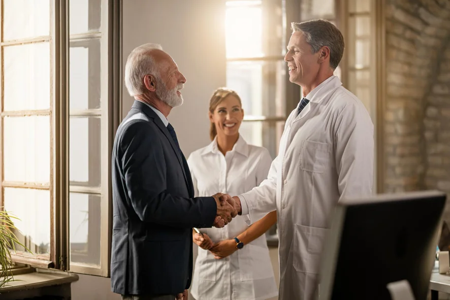 A figura representa a interação universidade-empresa, por meio de um senhor de terno (representando a universidade) e um profissional de jaleco (representando um médico ou diretor de hospital)