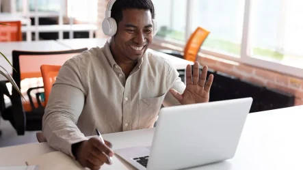 homem aluno de um dentre vários micro cursos, acenando para um laptop, como se estivera em uma aula online